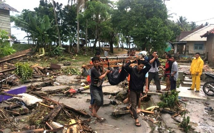 Petugas Basarnas dibantu warga mengevakuasi korban meninggal akibat tsunami di pesisir Cinangka, Serang, Banten, Minggu (23/12/2018). Foto : Antara