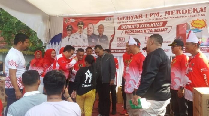 Penjabat Wali Kota Pekanbaru Muflihun dan Sekjen LPM RI Idham Dalimunthe memberikan kuis dan hadiah doorprize kepada warga yang ikut Gerak Jalan Sehat guna memeriahkan HUT LPM RI ke-23 dan Rakernas di Kota Pekanbaru. Foto: LPM Pekanbaru